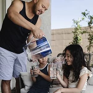 PUR pitcher being used to pour filtered water in a kitchen